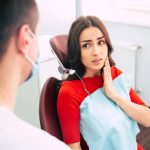 patient experiencing tooth pain while consulting a dentist before a tooth extraction procedure.