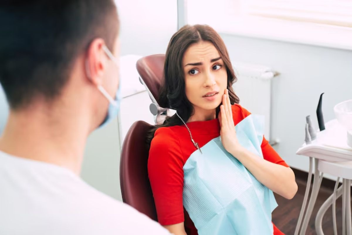patient experiencing tooth pain while consulting a dentist before a tooth extraction procedure.